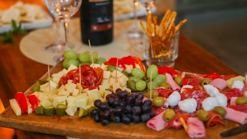 Tabla de aperitivo con quesos, embutidos, uvas, aceitunas y vino